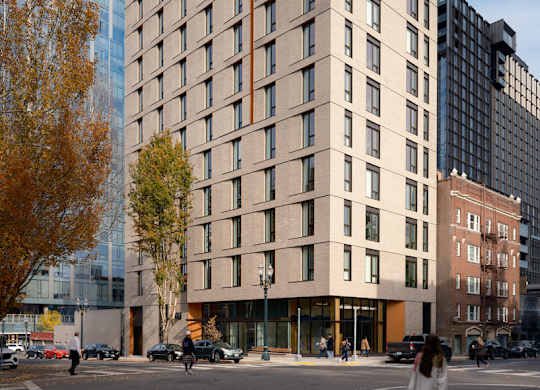 A tall building with many windows is surrounded by trees and other buildings.