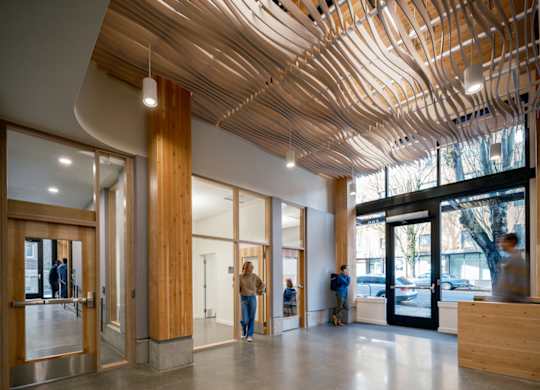 A modern interior with a wooden ceiling and people walking around.