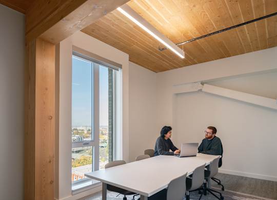 Two people sitting at a table in a room with wooden walls and ceiling.