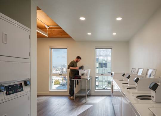 A man is standing in a kitchen with a window behind him.
