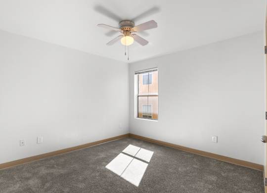 A room with a ceiling fan and a window.