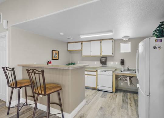A kitchen with a white refrigerator and wooden chairs.