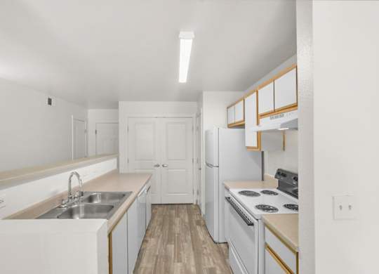 A white kitchen with a sink, stove, and cabinets.