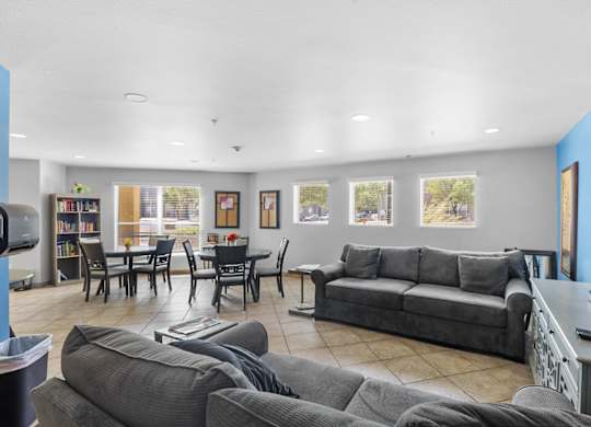 A living room with grey couches and a dining table.