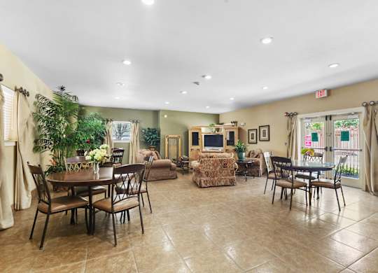 A spacious room with a dining table and chairs, a sofa, and a television.