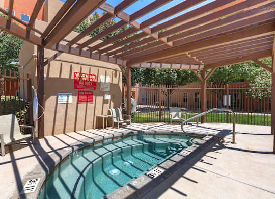 A pool with a wooden pergola over it.