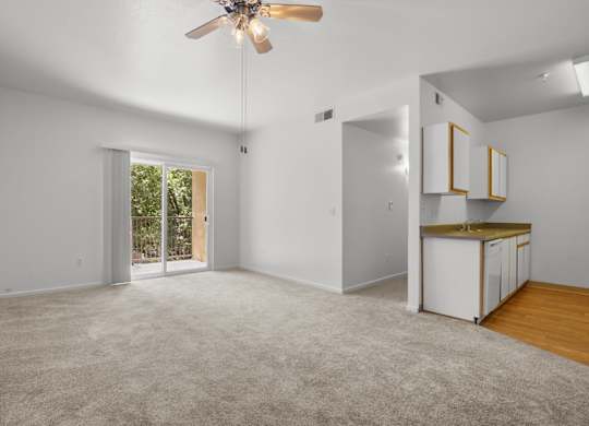 A spacious room with a ceiling fan and a small kitchenette.