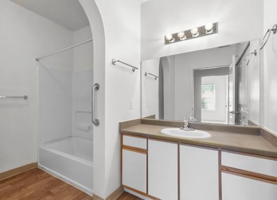 A bathroom with a sink, mirror, and shower.