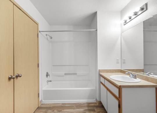 A bathroom with a wooden door and a white bathtub.