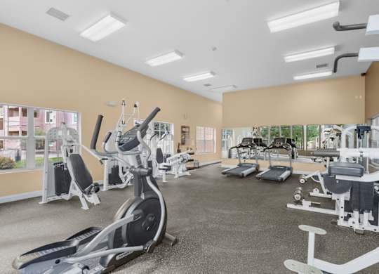 A spacious gym with a variety of equipment including treadmills, stationary bikes, and weight machines.