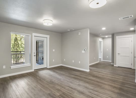 an empty living room with a kitchen in the background