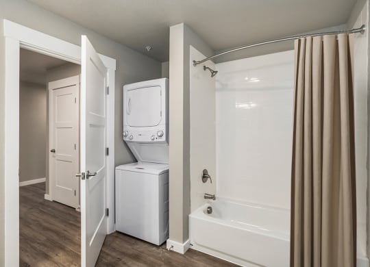 a bathroom with a washer and dryer in it and a shower and tub