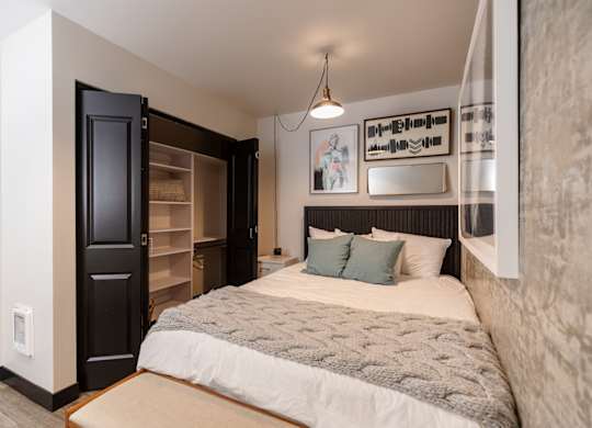A bedroom with a large bed and a black door.