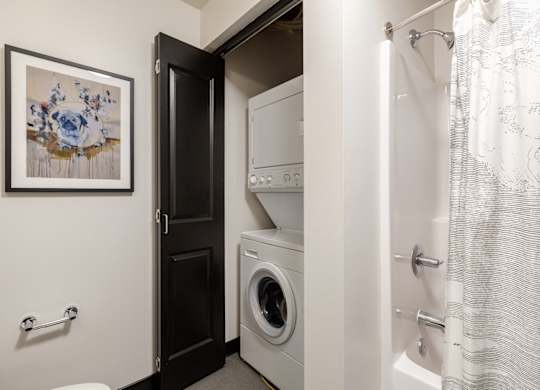 A bathroom with a washing machine and a shower.