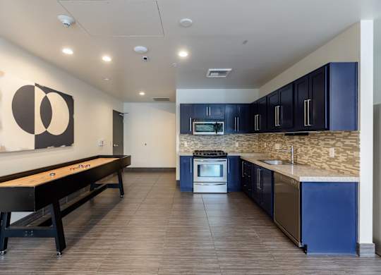 A modern kitchen with blue cabinets and a pool table.