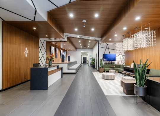 A modern office lobby with a long wooden hallway and a reception desk on the left.