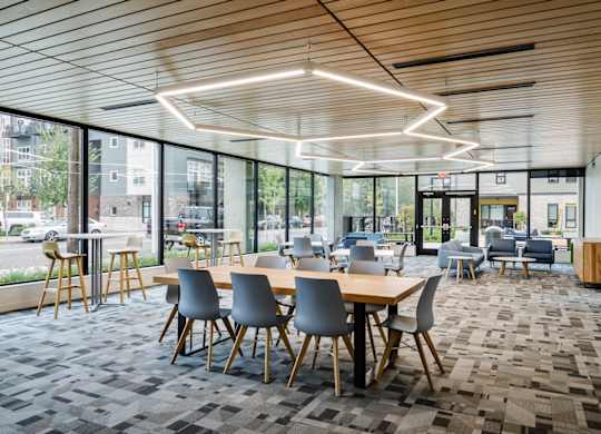 A modern dining area with wooden tables and grey chairs.