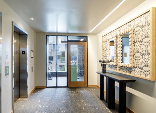 a lobby with glass doors and a mirror and a table at Slabtown Square Apartments, Portland , OR