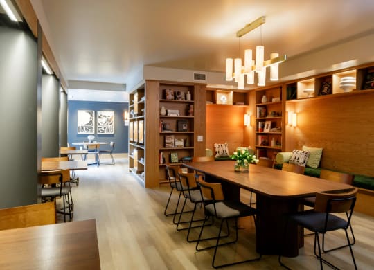 library with books, a long table and side individual tables at Slabtown Square Apartments, Portland , OR 97209