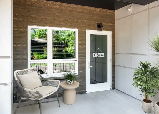 a porch with two chairs and a table and a door