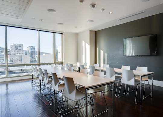A conference room with a long table and chairs with a city view through the windows.