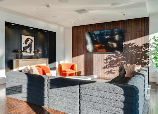 A living room with a grey couch and a television on the wall.