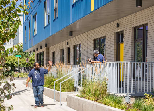 people walking down a sidewalk in front of a blue building