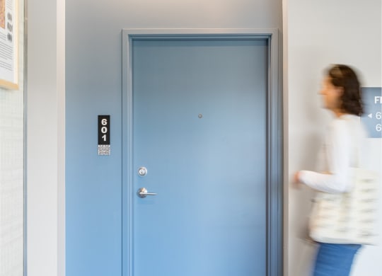 a woman walking out of a room with a blue door
