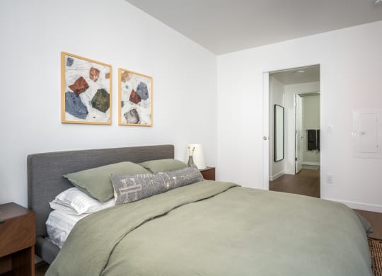 a bedroom with a large bed and two paintings on the wall at Slabtown Square Apartments, Portland , OR
