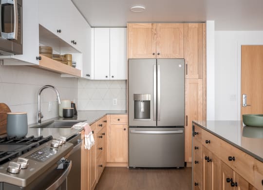 a kitchen with wooden cabinets and a stainless steel refrigerator at Slabtown Square Apartments, Portland ,Oregon, 97209