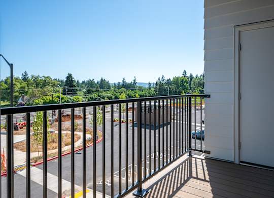 A balcony with a view of a road and trees.