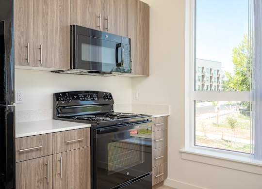 A black microwave is mounted on a wooden cabinet above a black stove.
