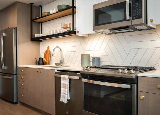 a kitchen with stainless steel appliances and wooden cabinets at Slabtown Square Apartments, Portland , OR