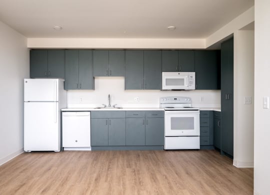 an empty kitchen with white appliances and blue cabinets