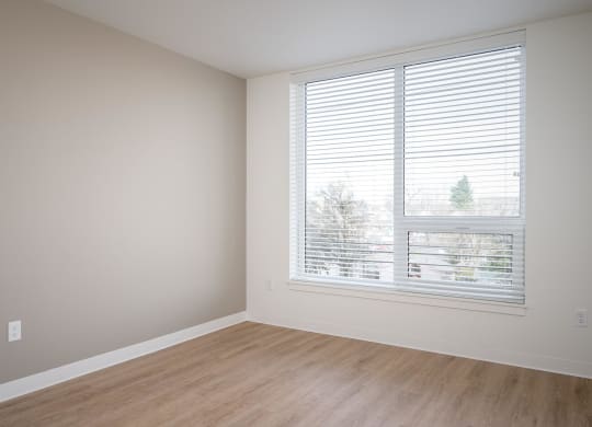 an empty room with a window and wooden floors