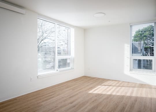 an empty room with two windows and a wooden floor