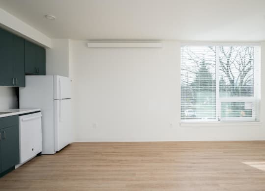an empty kitchen with a window and a white refrigerator