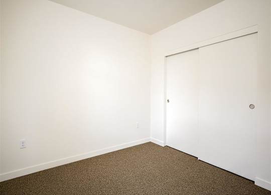 a bedroom with white walls and a door to a closet