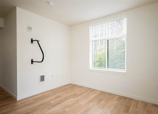 an empty room with a large window and wooden floors