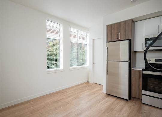 an empty kitchen with a stainless steel refrigerator and a window