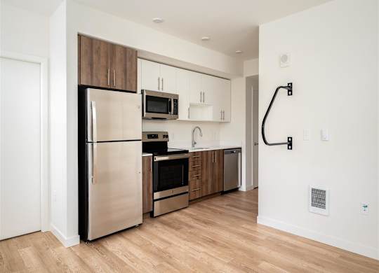 a kitchen with stainless steel appliances and a wood floor in an apartment