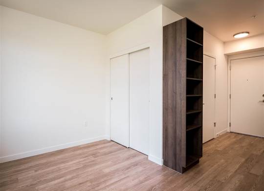 a bedroom with white walls and wood flooring and a close