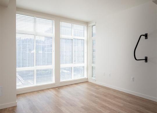 an empty living room with large windows and a wood floor