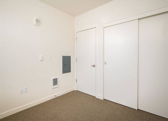 a bedroom with white walls and white doors and carpet