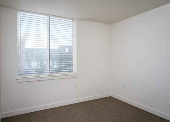 an empty room with a large window and white walls