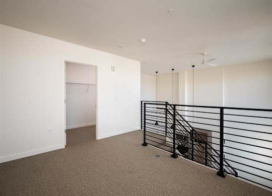 a room with white walls and a railing and a closet