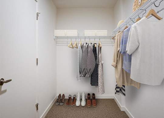 a walk in closet with a rack of clothes and shoes