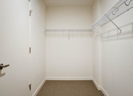 a room with white walls and a closet with wire shelving