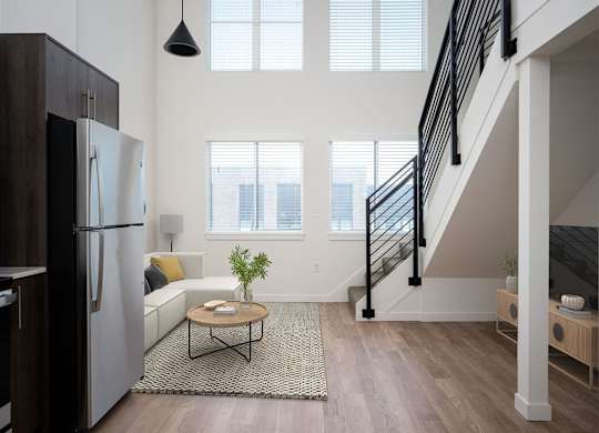 a living room with a refrigerator and a staircase