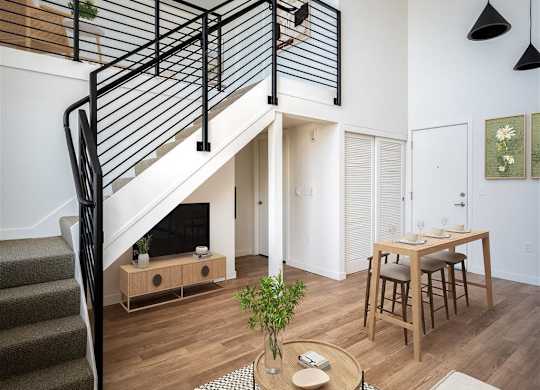 a living room with a staircase and a dining table